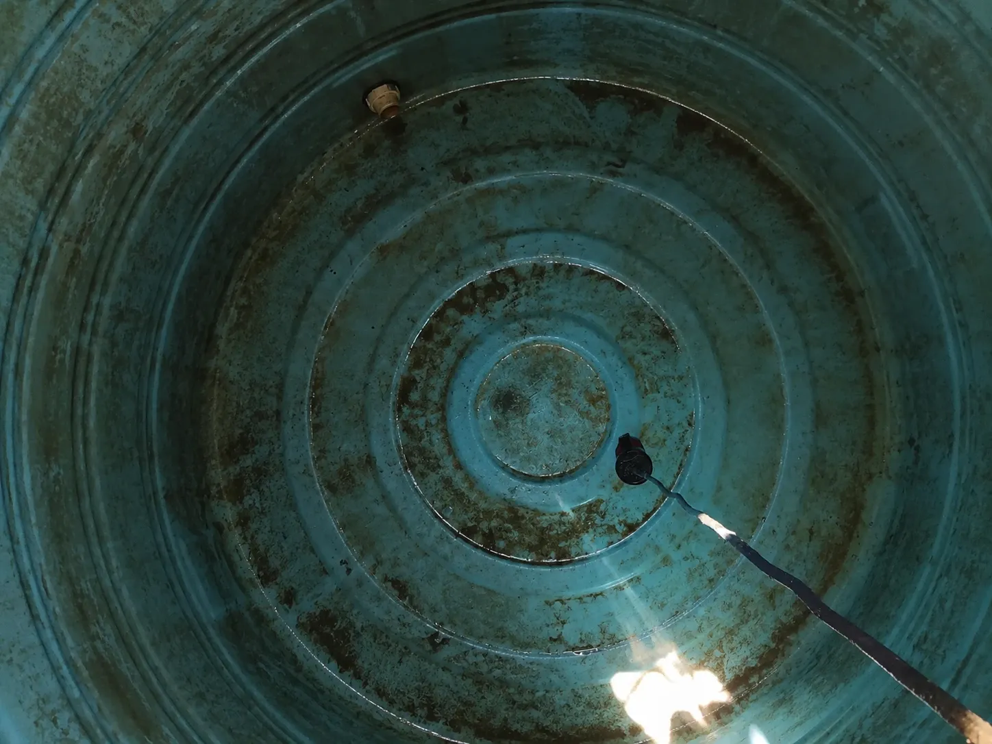 Unclean blue water tank interior with algae, sludge, bio-film and dirty standing water